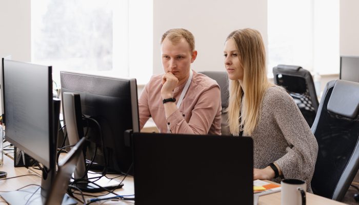 Full concentration at work. Group of young business people working and communicating while sitting at the office desk together with colleagues sitting in the background