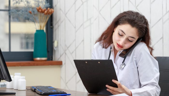 Young doctor sittin at the office and talking on the phone. High quality photo